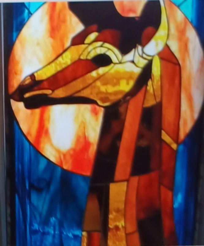 Heart of Africa — a large stained-glass giraffe in amber and bronze against a glowing sun and deep blue sky, by Kim’s Creative Cuts
